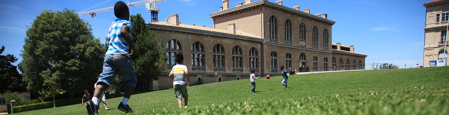 enfants courants sur une pelouse devant un bâtiment de l'Université d'Aix-en-Provence