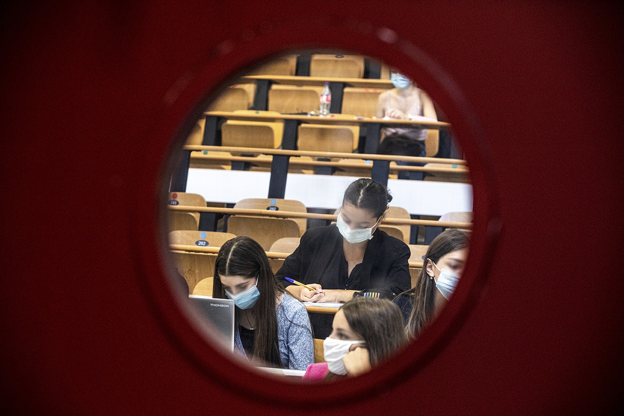 étudiante masquée vue depuis le hublot d'une salle de classe dans un amphithéâtre de faculté 