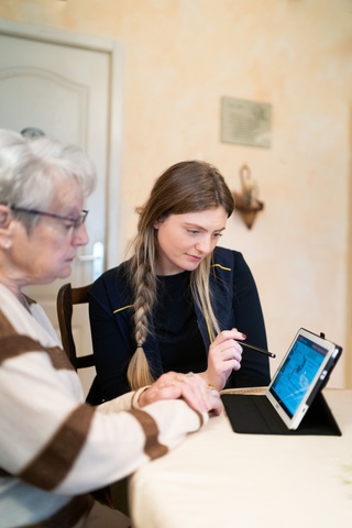 postière accompagnant une personne âgée pour la former sur l'utilisation d'une tablette numérique
