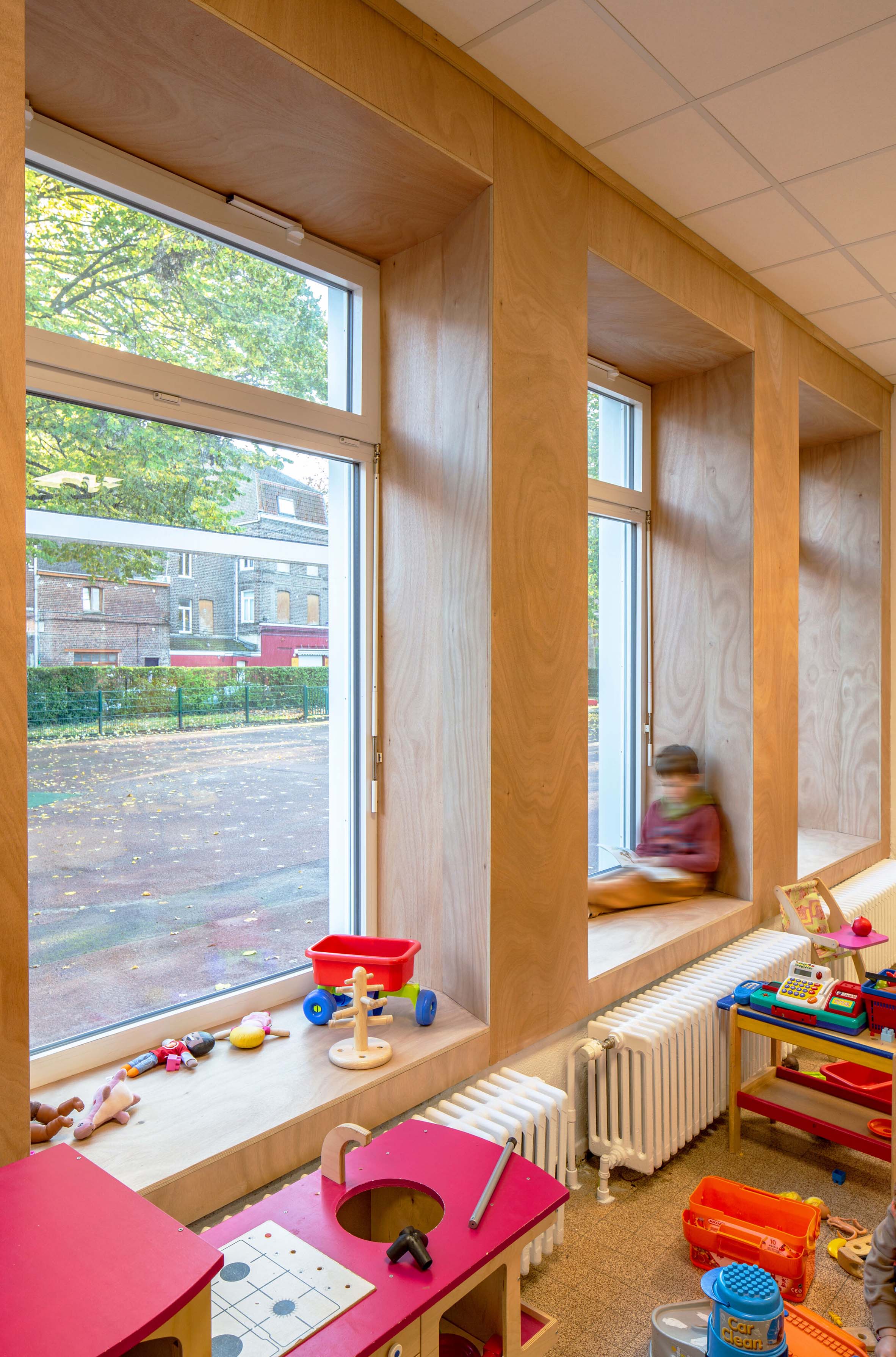 Un enfant lit près d'une fenêtre dans une salle de classe rénovée.