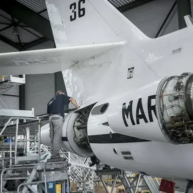 Un homme travaille à la maintenance d'un avion de l'armée française dans un atelier.