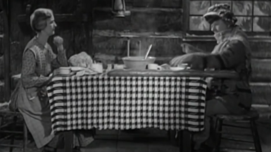 Image en noir et blanc d'une femme et un homme à table.