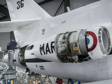 Un homme travaille à la maintenance d'un avion de l'armée française dans un atelier.