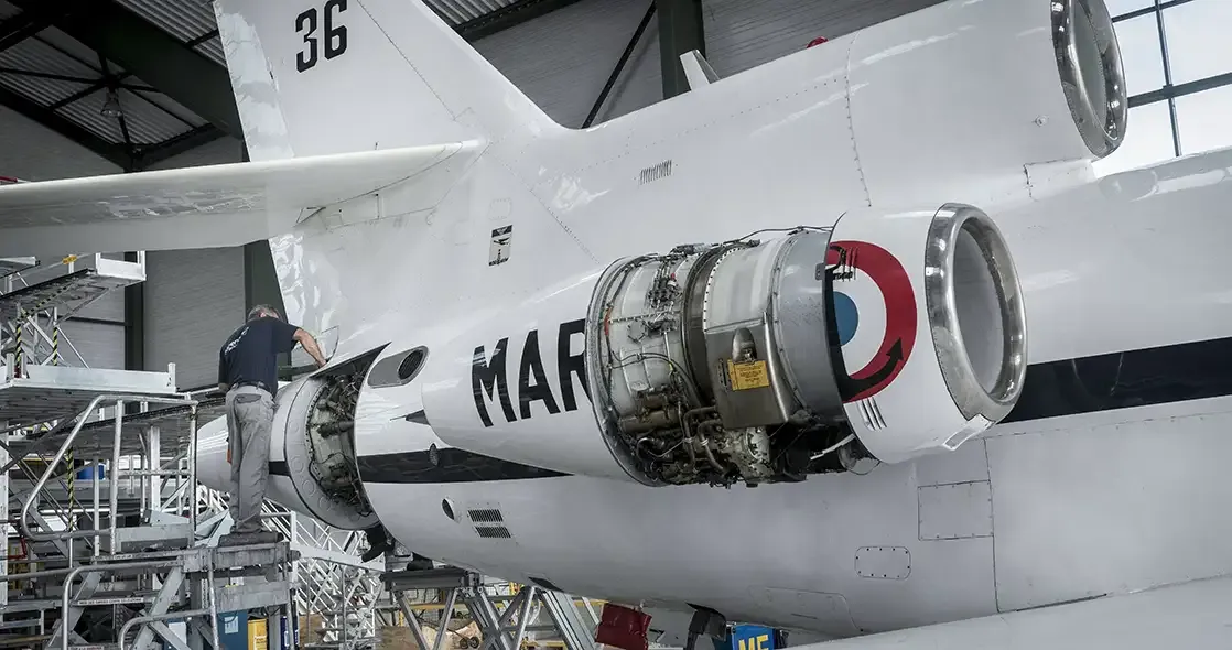 Un homme travaille à la maintenance d'un avion de l'armée française dans un atelier.